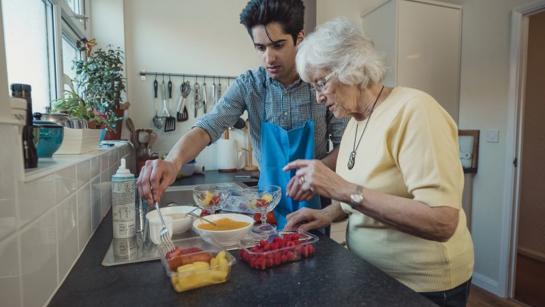 Male Care Worker Making Food With Resident